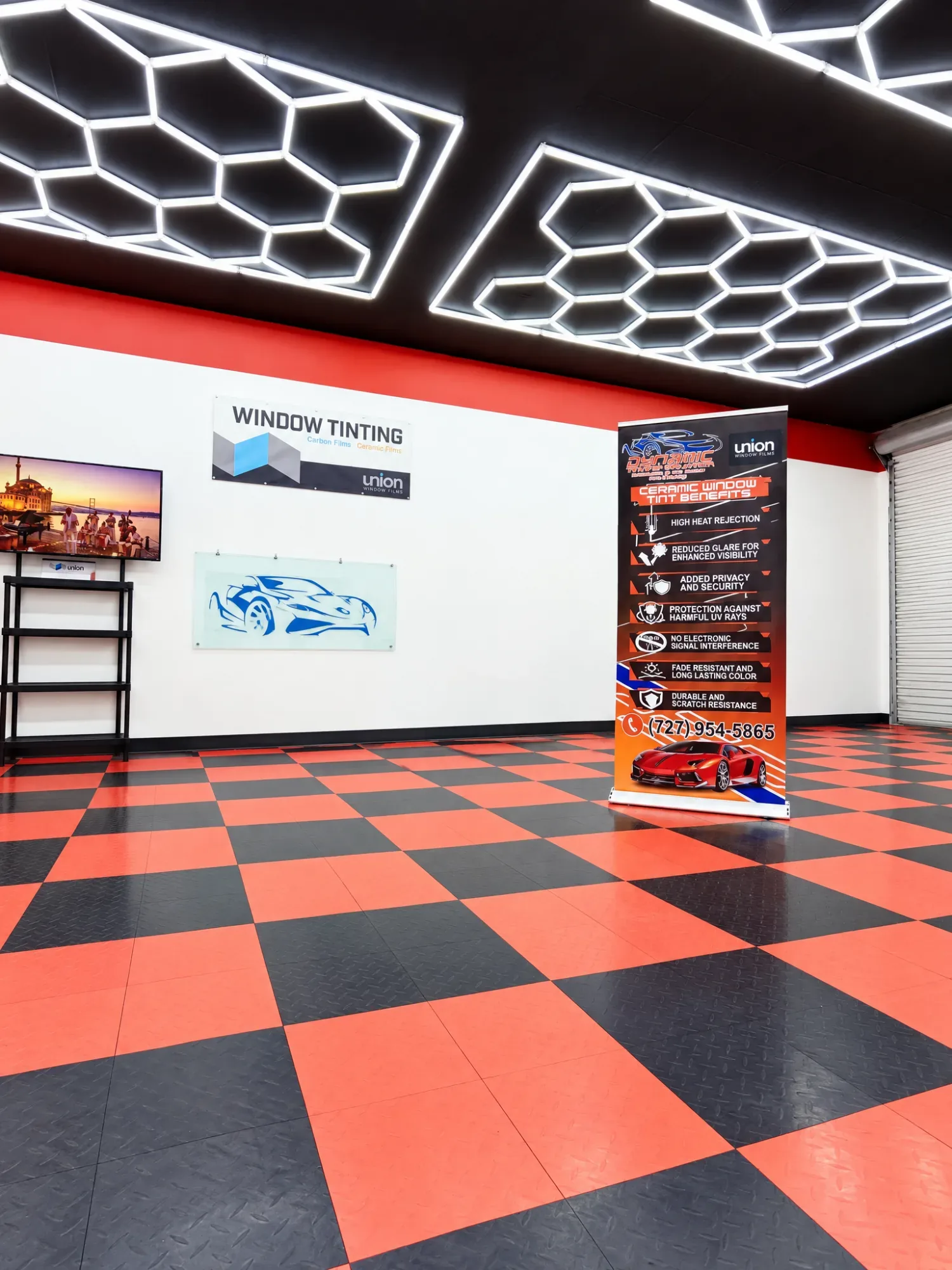 Inside the Dynamic Tinting Solution shop in Largo: their Union Window Films sign and their own banner under the hexagon lights