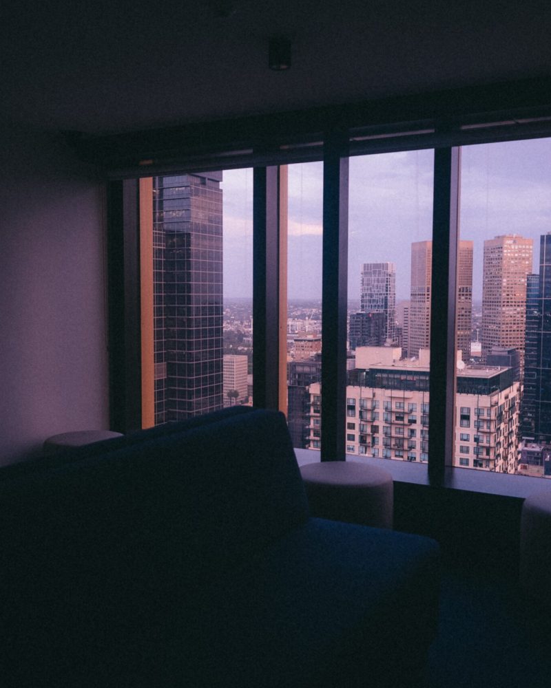 A small apartment with a large window with a view of an urban city architecture